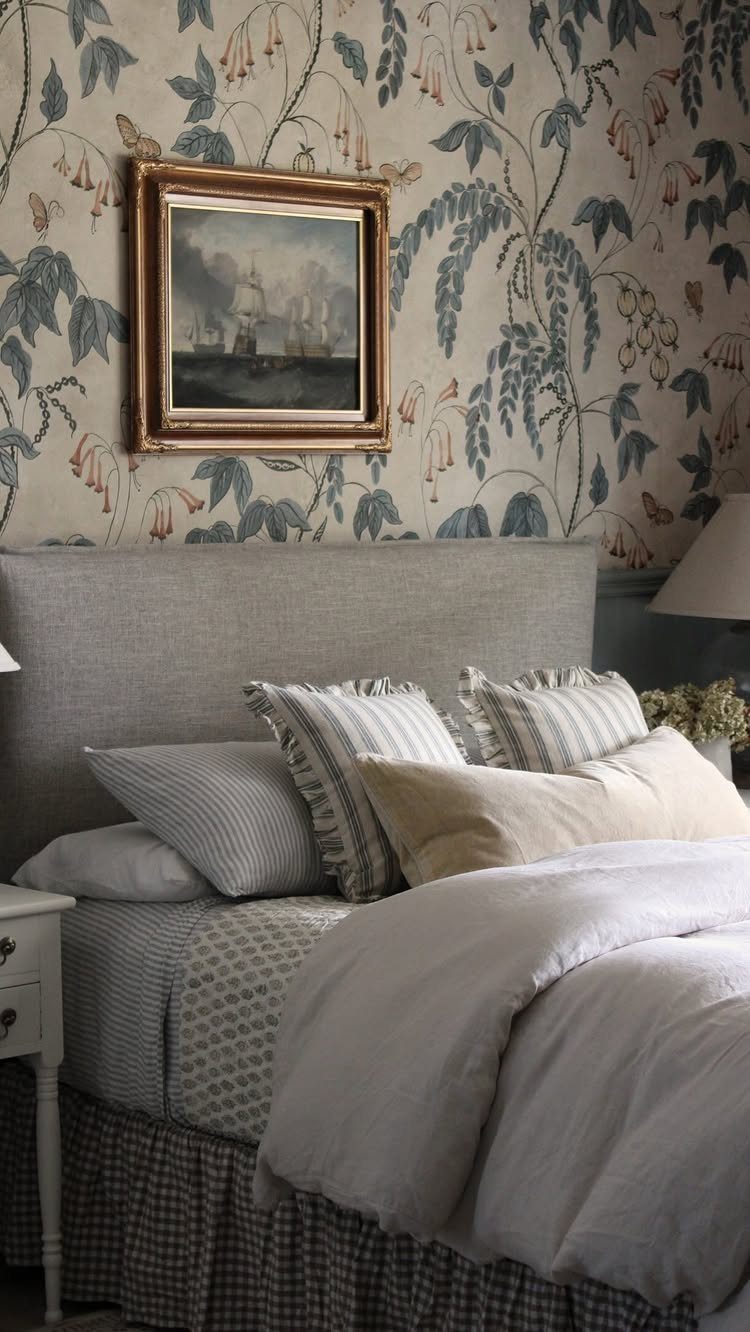 Blue floral wallpaper and beige bedding in a serene, classically styled bedroom setting.