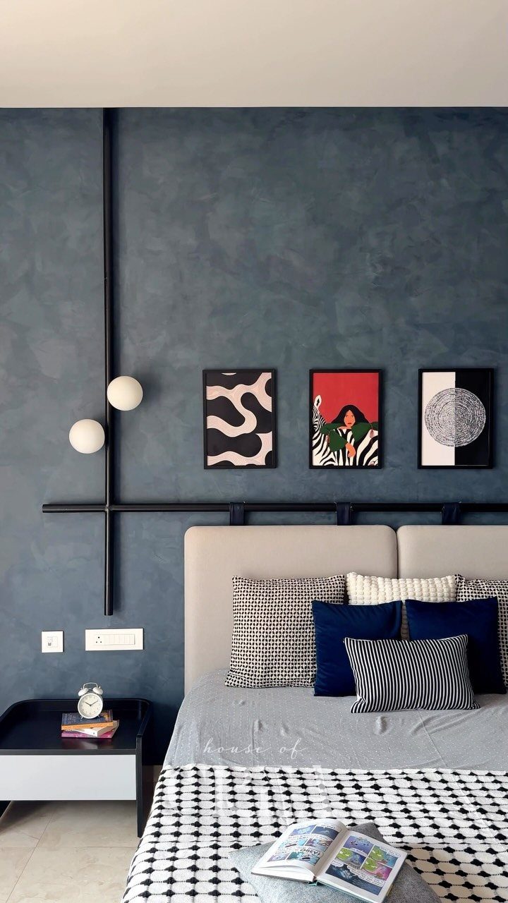 Dark blue bedroom wall featuring three small colorful art pieces above a beige headboard.