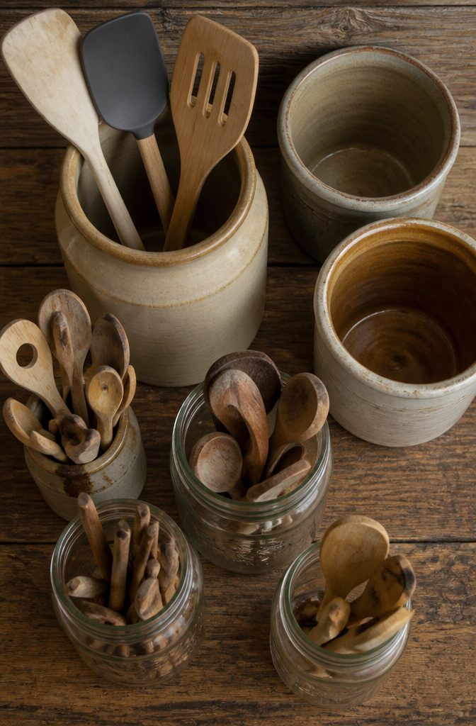 Glass jars and stoneware crocks arranged on kitchen shelves.