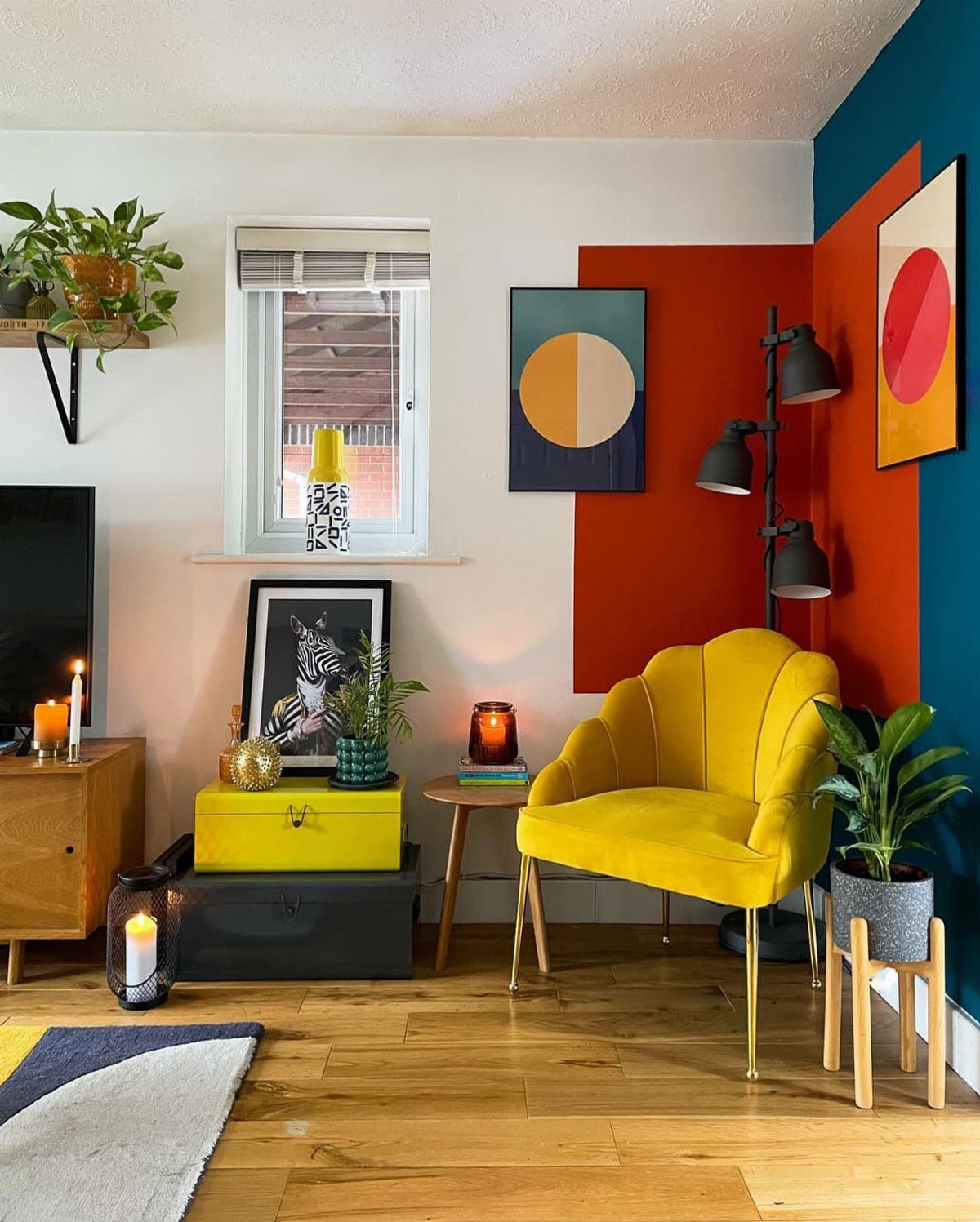 Yellow shell chair against a red and blue color-blocked wall with abstract art.