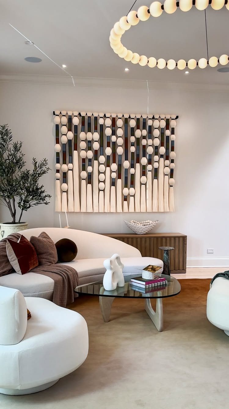 Large textured wooden wall art hanging above a white curved sofa in a living room.