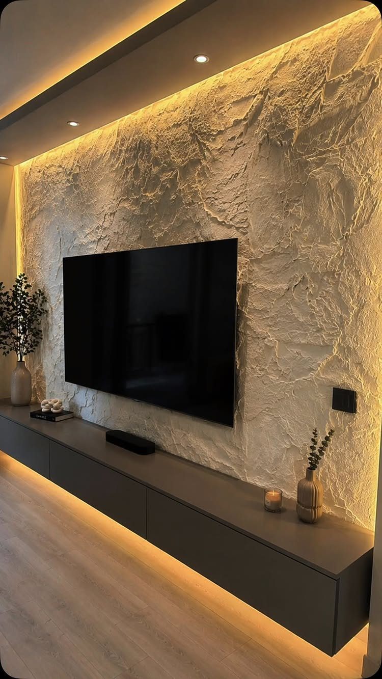 Textured stone accent wall with a mounted television and grey floating console.