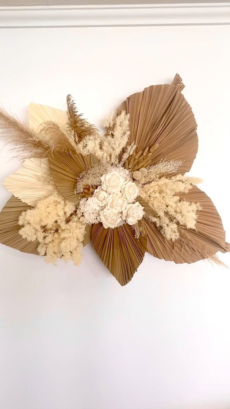 Dried pampas grass and palm leaf wall arrangement with white roses on white wall