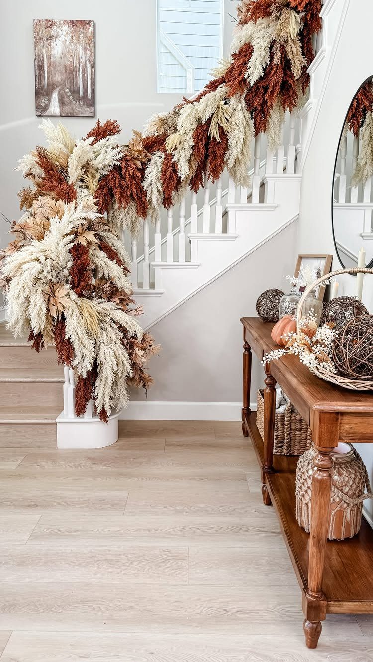 Pampas grass garland in cream and rust tones draped over a white staircase railing.