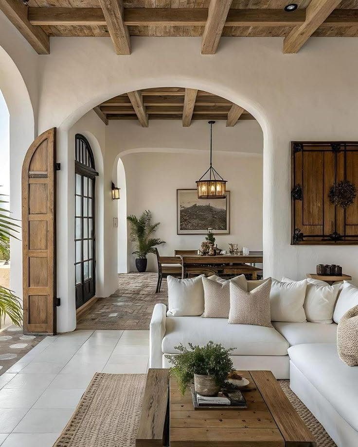 13 Spanish Style Living Room Decor Ideas with Warm Character 10 Spanish style living room with white walls, wooden beams, and arched doorways.