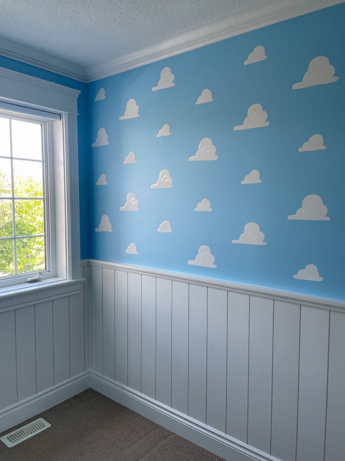 12 Toy Story Bedroom Ideas for Kids Who Love Woody and Buzz 9 Blue wall with white clouds and white wainscoting in a child's bedroom.