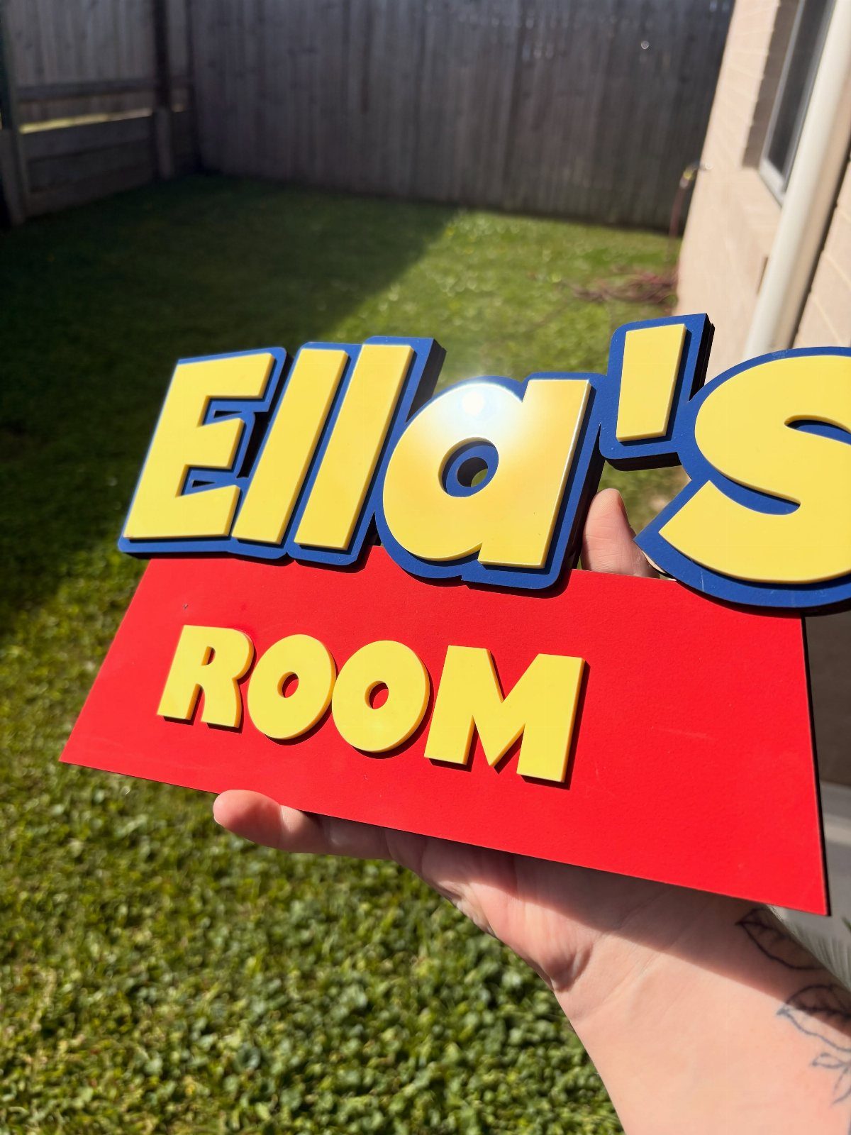 12 Toy Story Bedroom Ideas for Kids Who Love Woody and Buzz 8 Custom Toy Story themed name sign for Ella's room held over green grass.