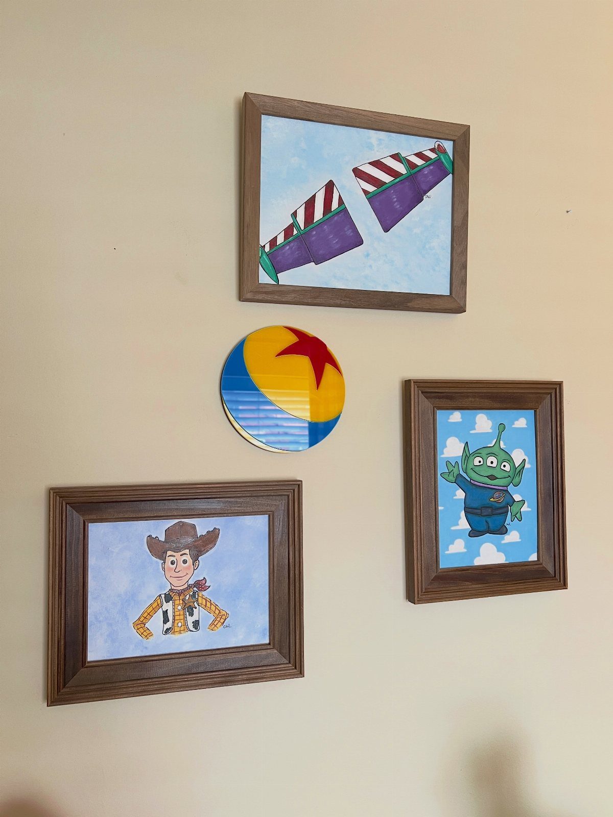 12 Toy Story Bedroom Ideas for Kids Who Love Woody and Buzz 5 Toy Story themed framed art and a Pixar ball plaque on a wall