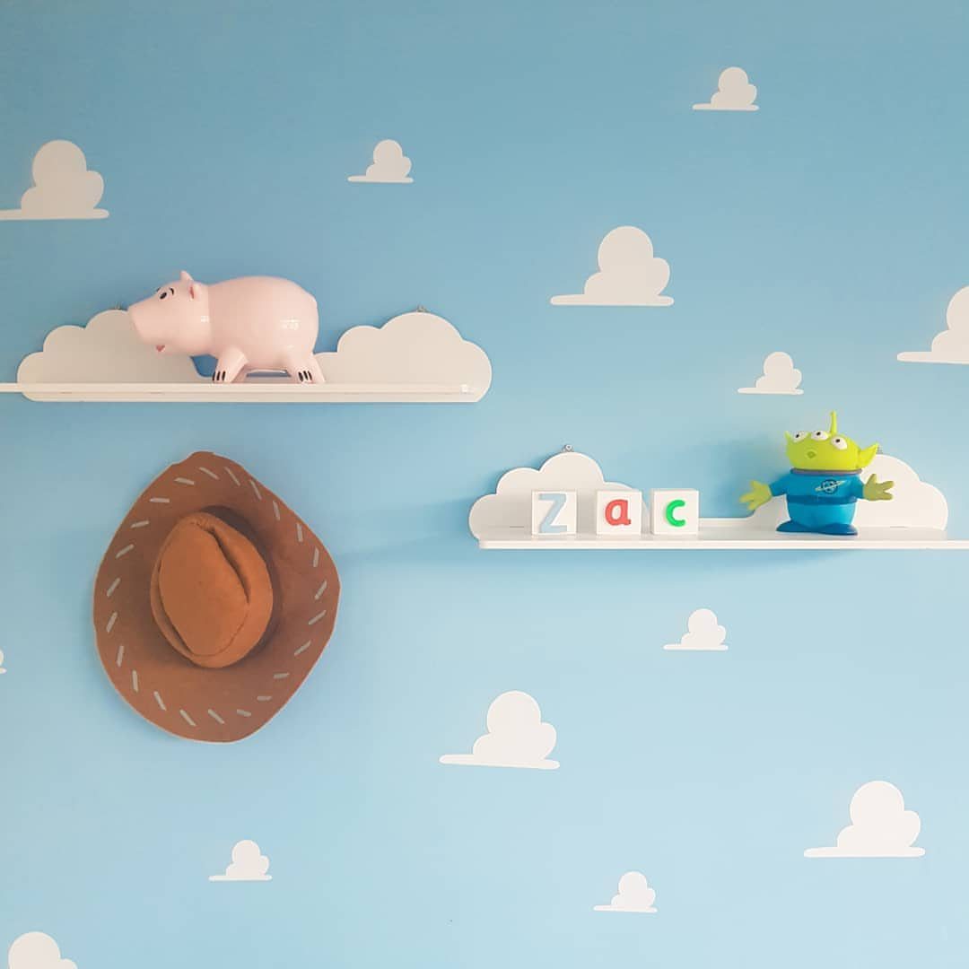 12 Toy Story Bedroom Ideas for Kids Who Love Woody and Buzz 4 Cloud-shaped shelves on a blue wall holding Toy Story characters and name blocks.